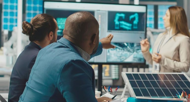 Équipe d'ingénieurs analysant des données sur écrans avec un panneau solaire au premier plan