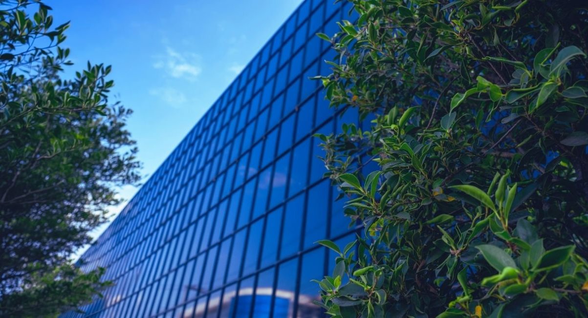 Façade vitrée d'un bâtiment tertiaire moderne encadrée par de la végétation