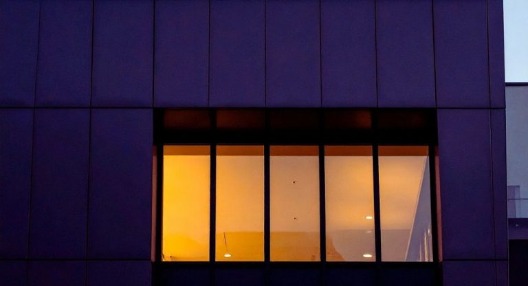 Façade d'immeuble de bureaux au crépuscule avec une rangée de fenêtres éclairées
