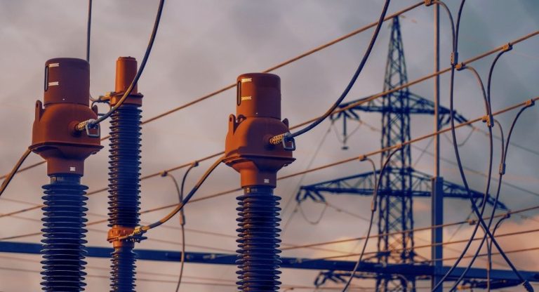 Isolateurs et pylône d'un poste électrique haute tension au coucher du soleil