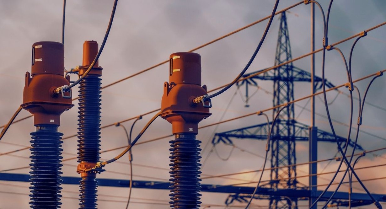 Isolateurs et pylône d'un poste électrique haute tension au coucher du soleil