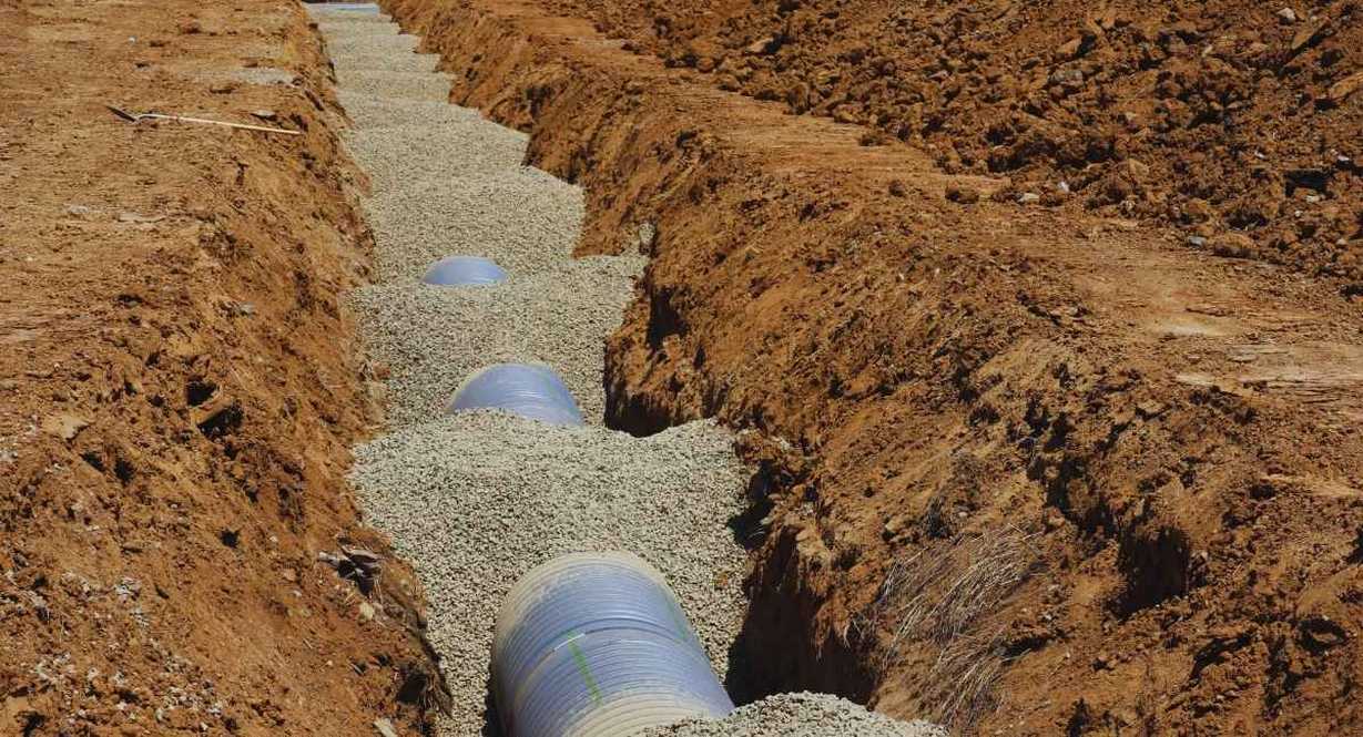 Tuyaux de drainage posés dans une tranchée creusée dans la terre